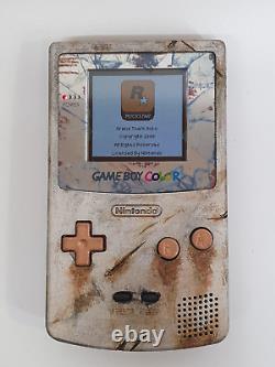 Console Game Boy Color en fer rouillé aspect vieilli avec écran LCD rétroéclairé.