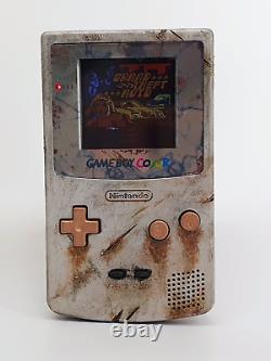 Console Game Boy Color en fer rouillé aspect vieilli avec écran LCD rétroéclairé.